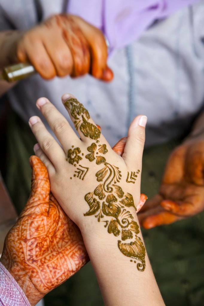 High angle close up of henna tattoos being put on hand.